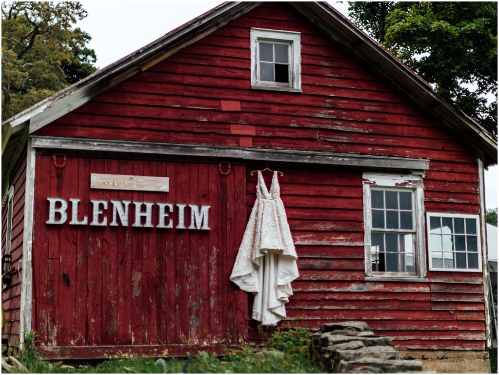 Wedding dress hangs on a red barn with the Blenheim sign