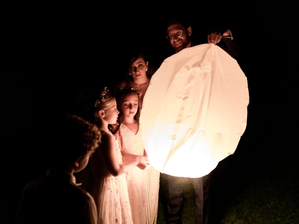 The bride and groom stand with children to light a big lantern.