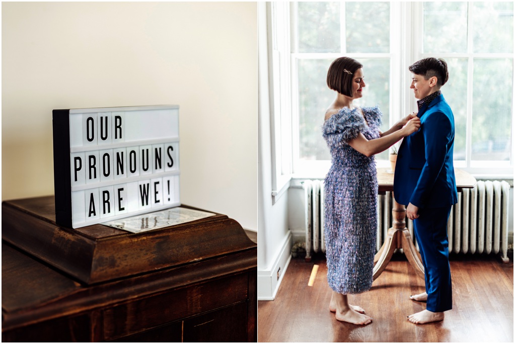 A sign reads "our pronouns are we." A woman in a blue dress helps her fiancee put on her jacket.